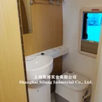 Compact bathroom inside the Airstream Allie caravan featuring a modern sink, integrated toilet, and wood-panel accents.
