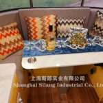Airstream Allie caravan dining nook with chevron cushions, blue embroidered runner and a bottle of Hessenay on the table