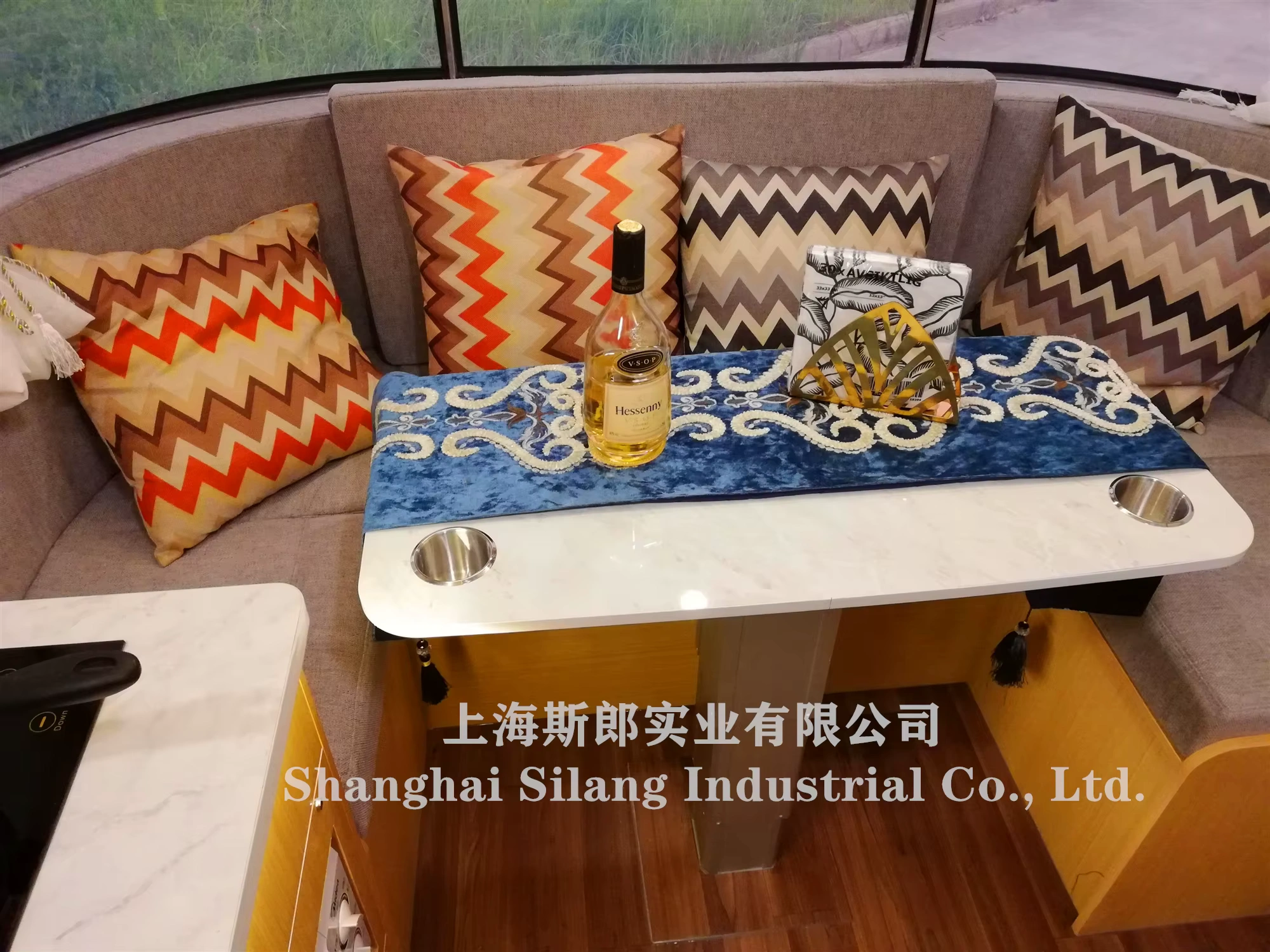 Airstream Allie caravan dining nook with chevron cushions, blue embroidered runner and a bottle of Hessenay on the table
