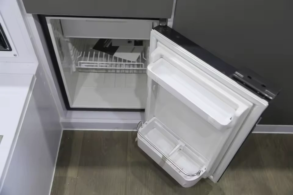 Open 50L fridge freezer inside the Black Betty Skadoo off-road camper trailer showing internal storage shelving.