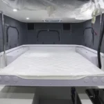 The interior of the Black Betty Skadoo off-road truck camper featuring a spacious queen-size sleeping area and kitchen.