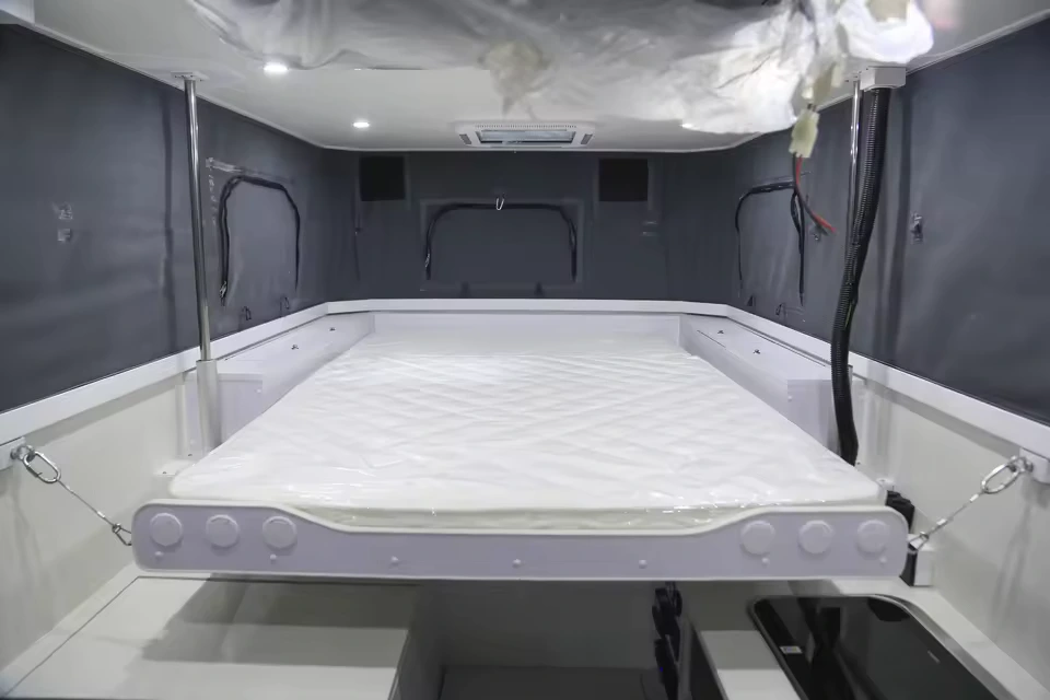 The interior of the Black Betty Skadoo off-road truck camper featuring a spacious queen-size sleeping area and kitchen.