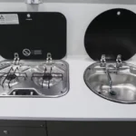 Modern integrated kitchen setup with a two-burner stove and a stainless steel sink for Black Betty Skadoo off-road RVs.