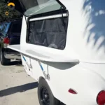 Eezon Eddy midsize caravan features an exterior fold-out kitchen shelf and awning setup for off-grid camping adventures.