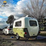 Eezon Eddy midsize caravan being towed by a silver vehicle at a scenic campsite for outdoor travel adventures.