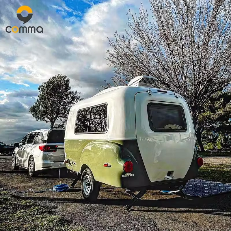 Eezon Eddy midsize caravan being towed by a silver vehicle at a scenic campsite for outdoor travel adventures.