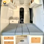 Modern interior view of the Eezon Eddy midsize caravan showing a cozy sleeping area, kitchen galley, and storage.