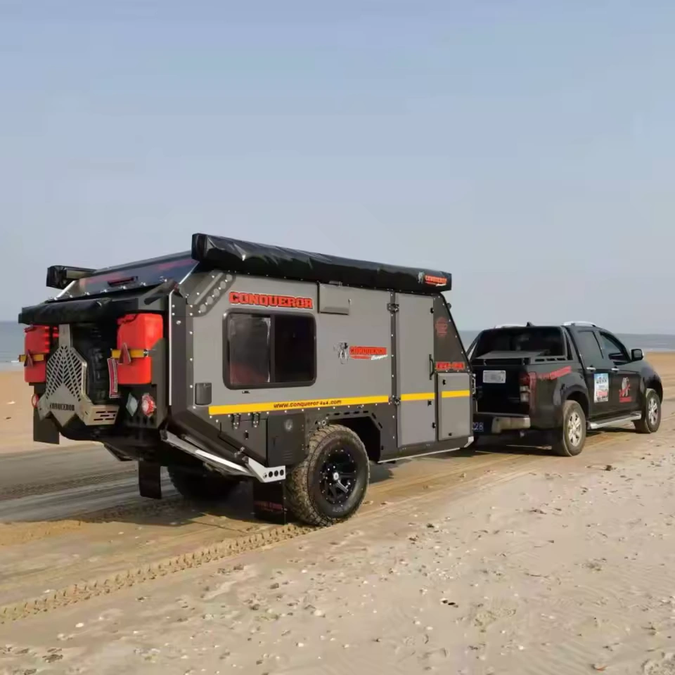 Gutsy Gary Conqueror off-road camper trailer hitched to pickup on beach sand, awning and reinforced chassis visible