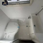 Compact white bathroom interior of a Black Rhino hybrid off-road caravan featuring a toilet, shower, and modern sink.