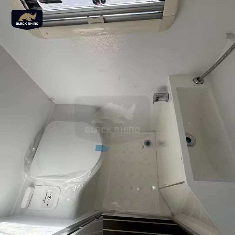 Compact white bathroom interior of a Black Rhino hybrid off-road caravan featuring a toilet, shower, and modern sink.