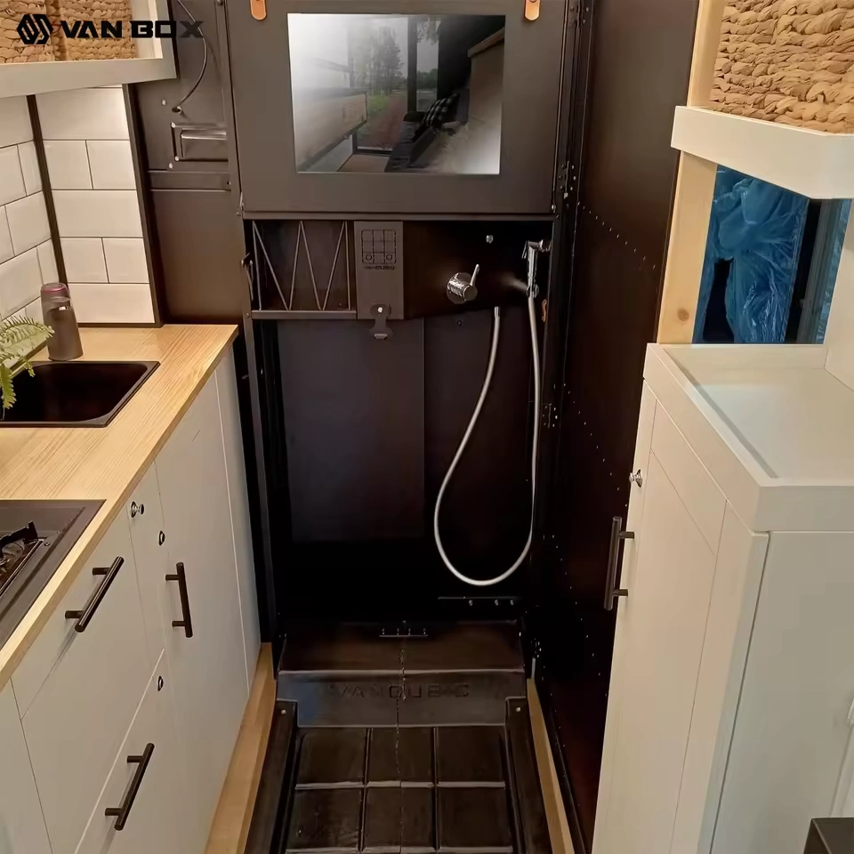 Modular campervan interior showing compact shower stall, handheld showerhead, sink, kitchenette and cabinetry — CODE 2603