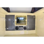 Premium interior entertainment setup in the Offroad Olly RTT caravan featuring a TV, audio system, and storage cabinets.