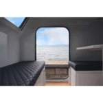 Interior view of the Offroad Olly RTT camper trailer featuring comfortable sleeping benches and a scenic water view.