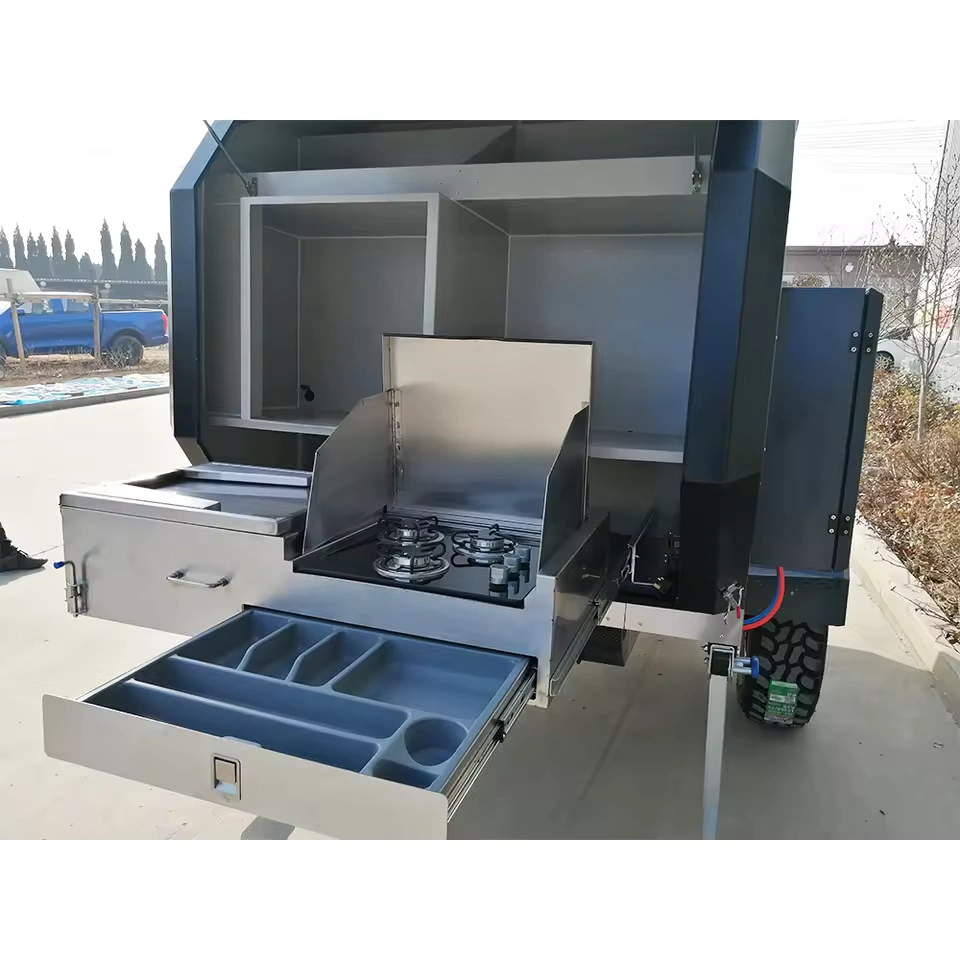 Offroad Olly RTT camper trailer features a slide-out stainless steel outdoor kitchen with a stove and storage drawer.