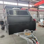 Popup Poppy off-road mini caravan in factory showing rooftop solar panel, hot-dipped galvanised chassis and front box