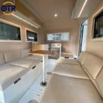 Retro Rex teardrop camper interior with beige seating, foldable dining table, kitchenette and windows for weekend getaways