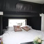 Roming Romeo off-road mini caravan interior featuring queen bed, decorative cushions, white bedding and pop-top canvas roof
