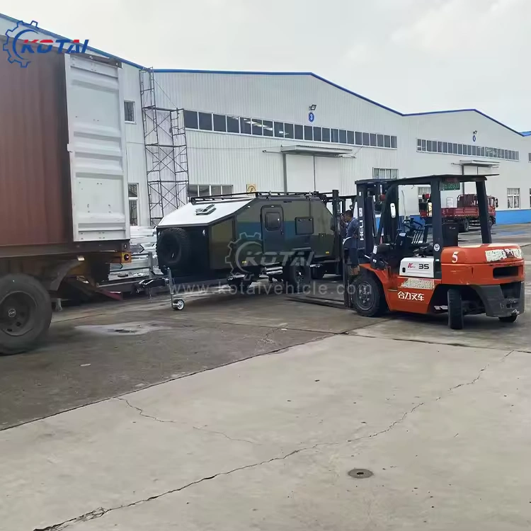 Rugged Roy off-road teardrop trailer in olive drab being forklift-loaded into a shipping container at factory yard