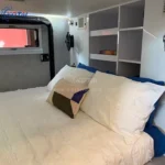 A view inside the cozy and modern queen-size sleeping area of the Rugged Roy off-road teardrop travel trailer caravan.