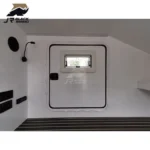 Interior view of the Shark I mini camper trailer featuring a white door, window, wall-mounted lamp, and modern flooring.