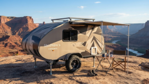 A Shidhani teardrop mini caravan parked on a desert cliff overlooking a canyon during a camping adventure trip.