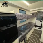 Interior view of the Black Rhino off-road caravan showing bunks with protective plastic and a sleek modern kitchen unit.