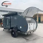 Side profile of the WECARE Basic Teardrop Mini Caravan with its rear hatch open showing kitchen storage compartments
