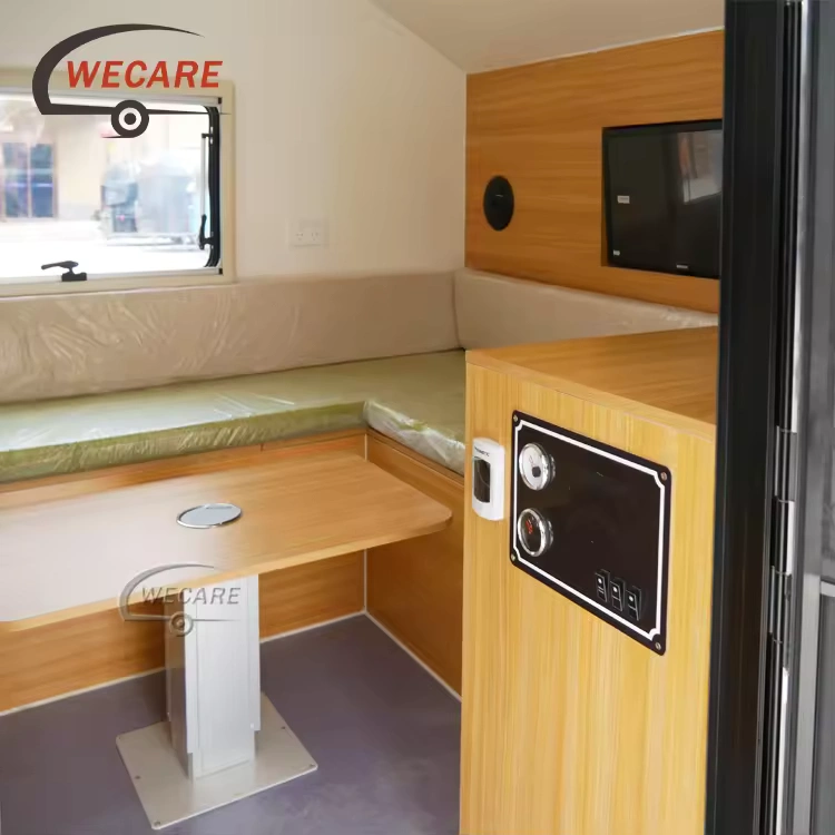 Interior view of the WECARE Teardrop Camper showing the convertible dining table area, plush seating, and wood finishes.