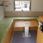 Interior view of the WECARE Teardrop Camper showing the seating area, adjustable table, and window in a new caravan.