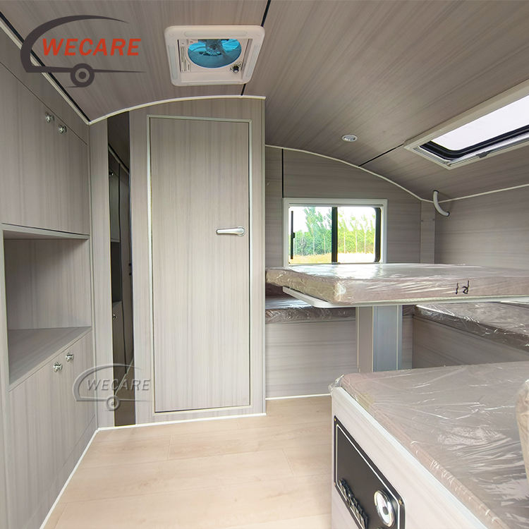 Modern, premium light-wood interior of a WECARE teardrop mini caravan with an ensuite door and space-saving furniture.