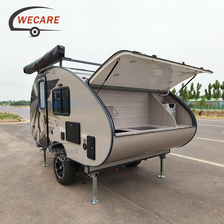 WECARE off-road teardrop mini caravan with an open rear outdoor kitchen, solar panel, and awning parked on a road.
