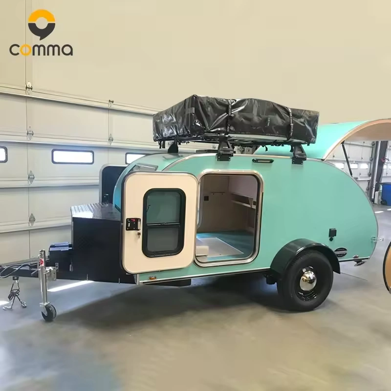 The Cody Compact mini teardrop caravan from Comma with an open side door, roof storage, and sleek aluminum body.