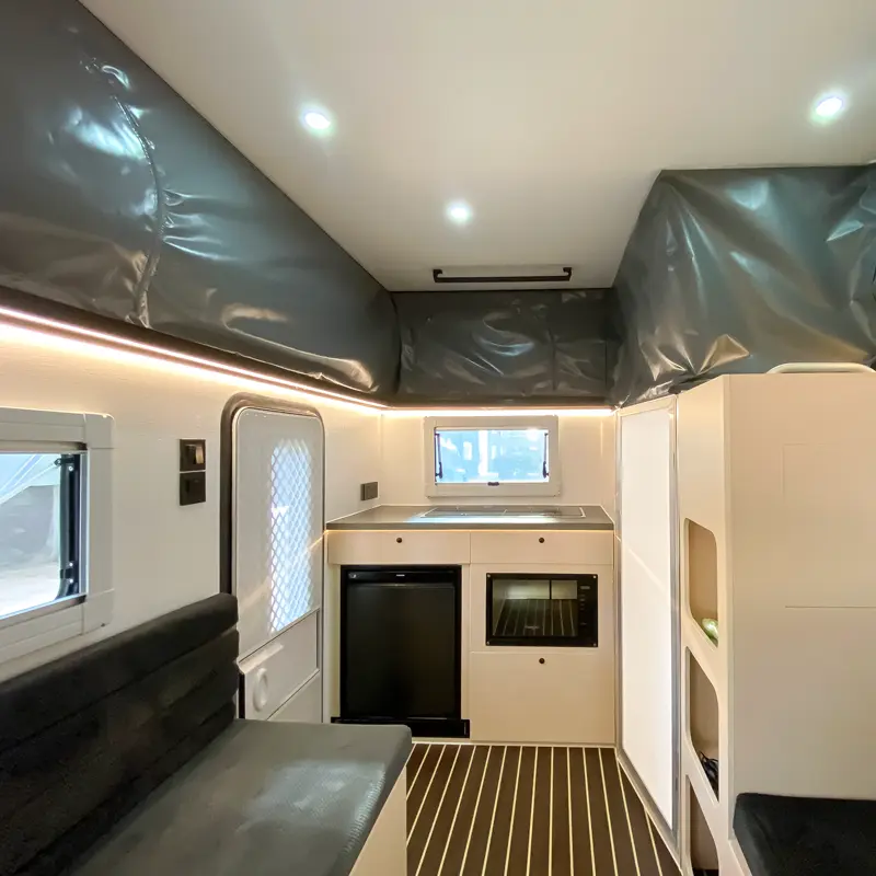 Modern interior of the Perry Popup hybrid caravan featuring a kitchenette, comfortable seating, and LED strip lighting.